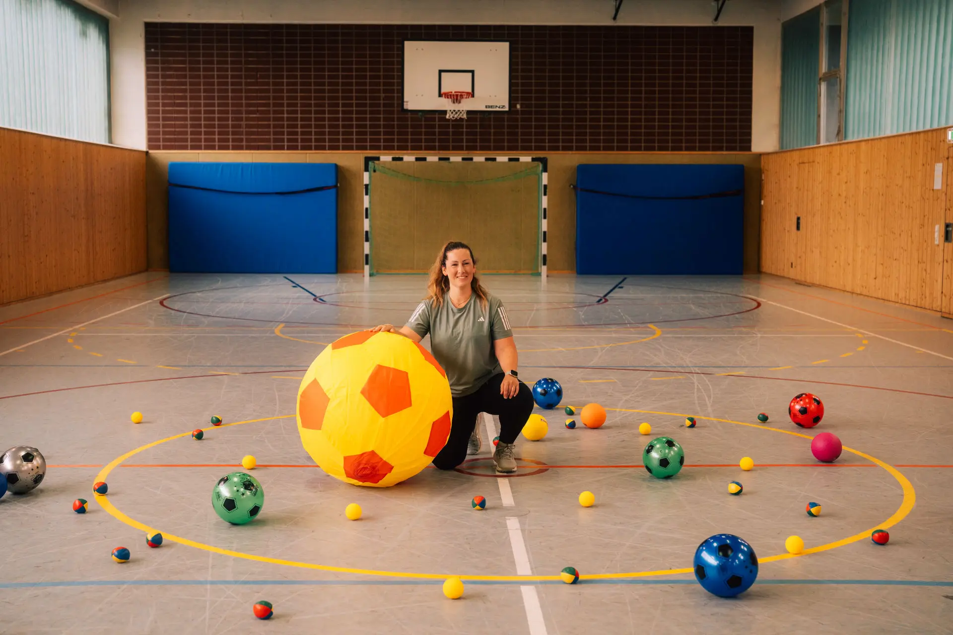 Kinder in Bewegung von Lisa Haas - Foto zeigt Lisa Haas in der Turnhall mit vielen Bällen und einem sehr großen Ball